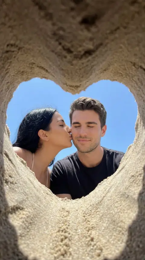A beautiful beach kiss framed in a heart-shaped frame of gravel