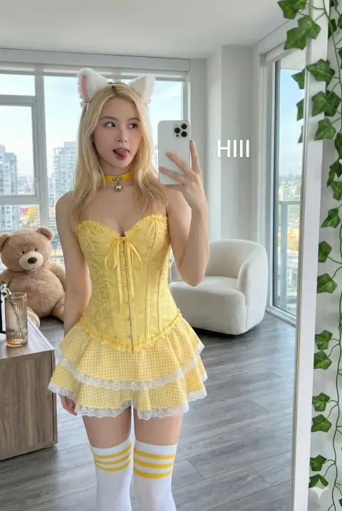 A cheerful selfie of a playful girl with cat ears in front of the floor-to-ceiling window in the sunshine
