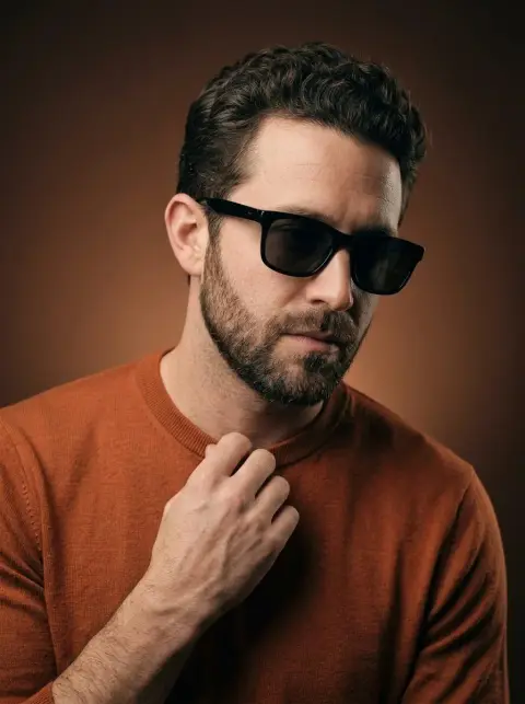 A confident and stylish man with burnt orange tones under the movie light and shadow