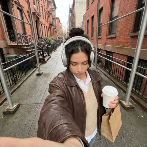 A cozy girl holding a cup of coffee walks on a red brick street on a cloudy day