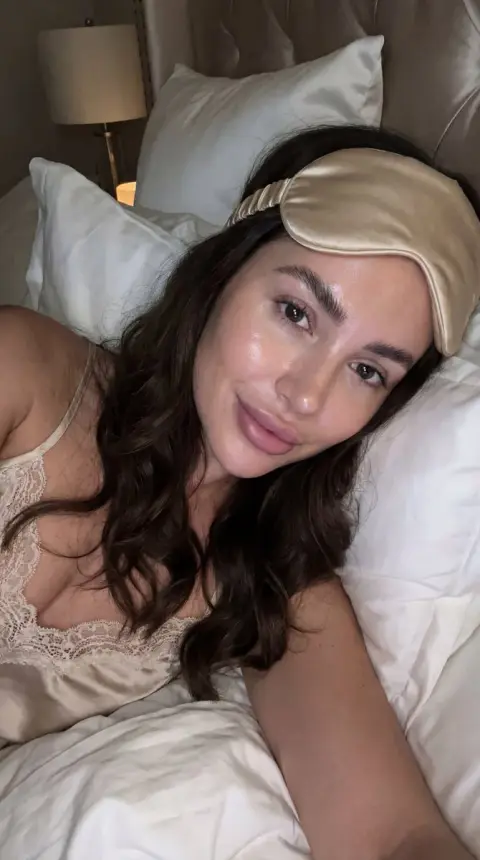 A no-makeup selfie in a luxurious bedroom after late-night skin care