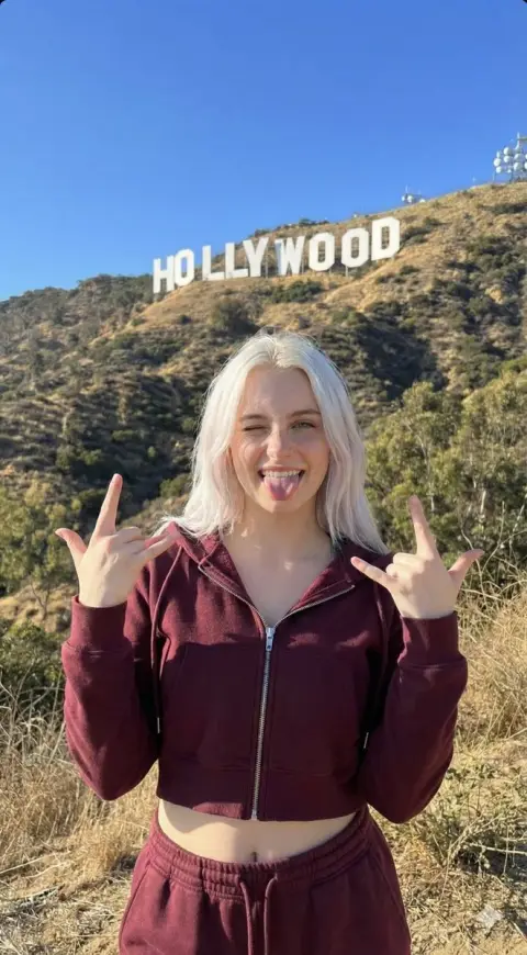 A playful sweet girl making the LA sign under the Hollywood sunshine