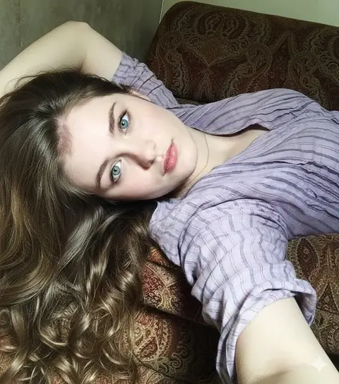 Beautiful girl with turquoise eyes taking selfie on sofa