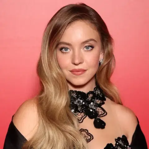 Black lace actress on the red carpet against the coral pink wall