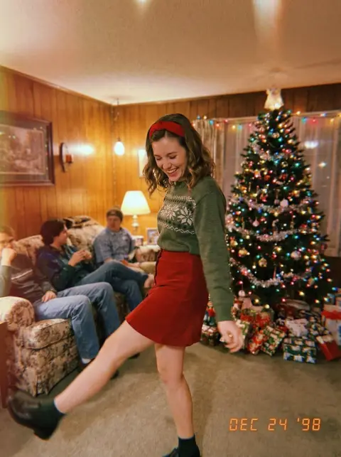 Blonde girl dancing casually at Christmas party under retro film texture