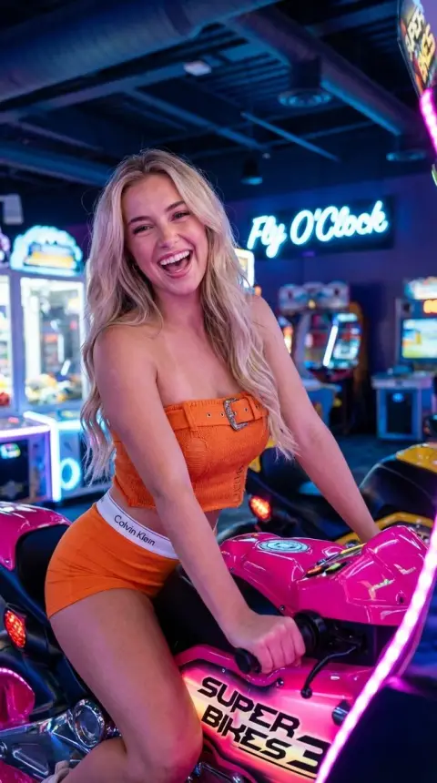 Blonde sweetheart riding pink motorcycle in neon arcade