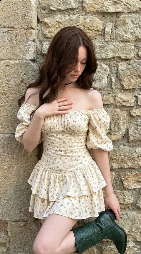 Bohemian girl in floral dress in front of mottled stone wall