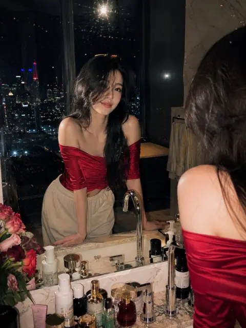 Cinematic photo of a woman in red in a luxurious bathroom under the city night view