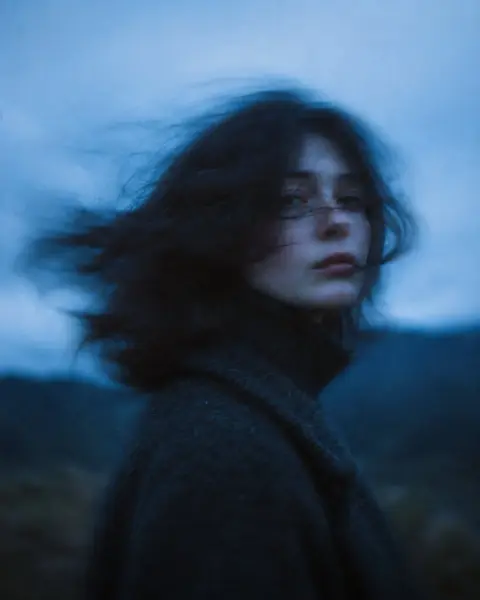 Cinematic portrait of woman with long hair blown by wind at twilight