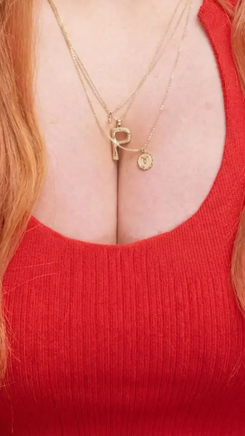Close-up of the lady in red wearing golden letter necklaces