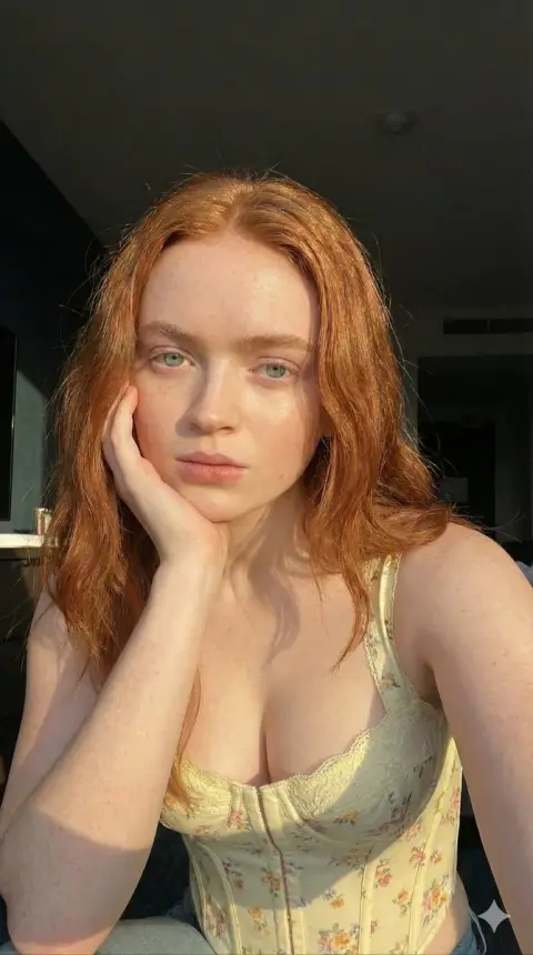 Close-up of blond girl with freckles bathing in golden sunshine