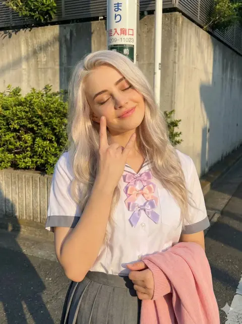 Close-up of white-blond girl in school uniform smiling under the golden sunset