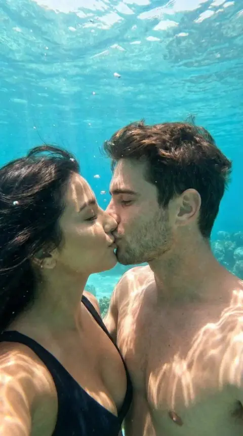 Deep underwater kiss with dappled light and shadow