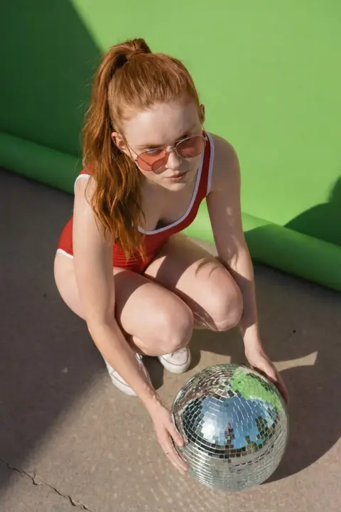 Disco girl in red in front of green wall