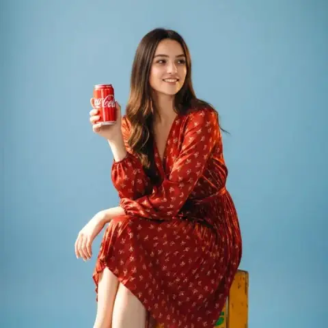 Fish eyes looking down at the interesting moment of a girl in a red dress holding a Coke in the air