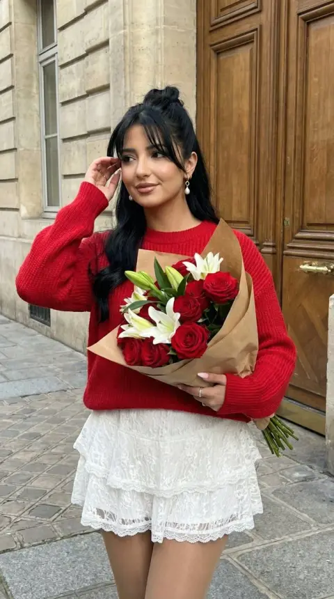 Girl in red sweater holding flowers on the street in autumn