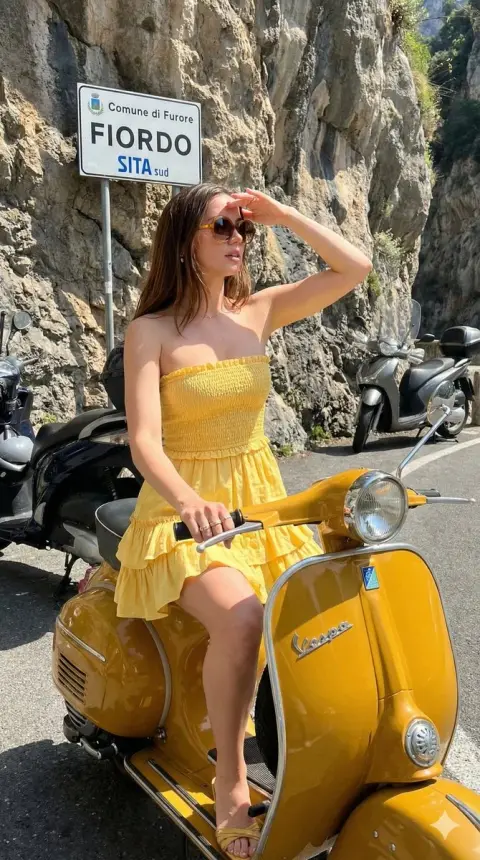 Girl in yellow dress and retro scooter in the sunshine on the Amalfi Coast