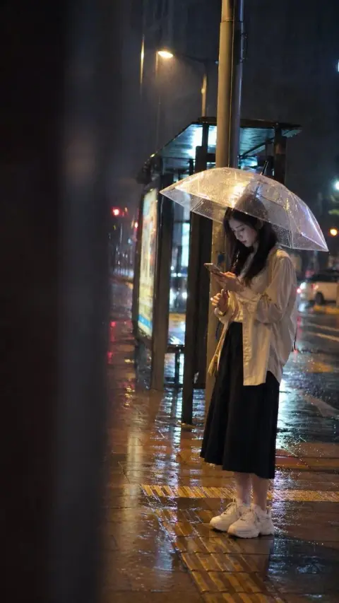 Girl waiting at the bus stop on a rainy night