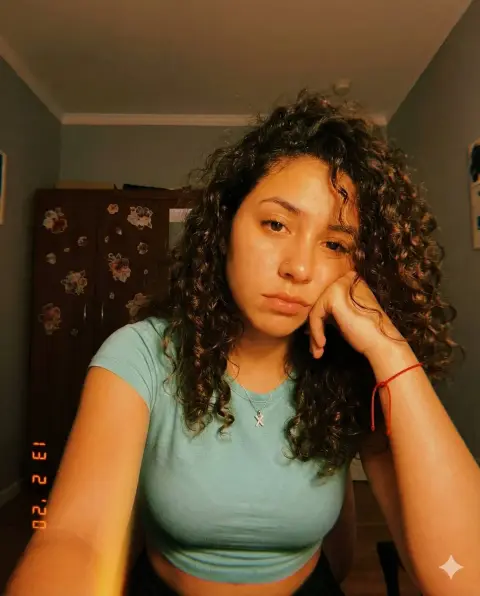 Girl with retro curly hair taking selfie under warm bedroom light and shadow