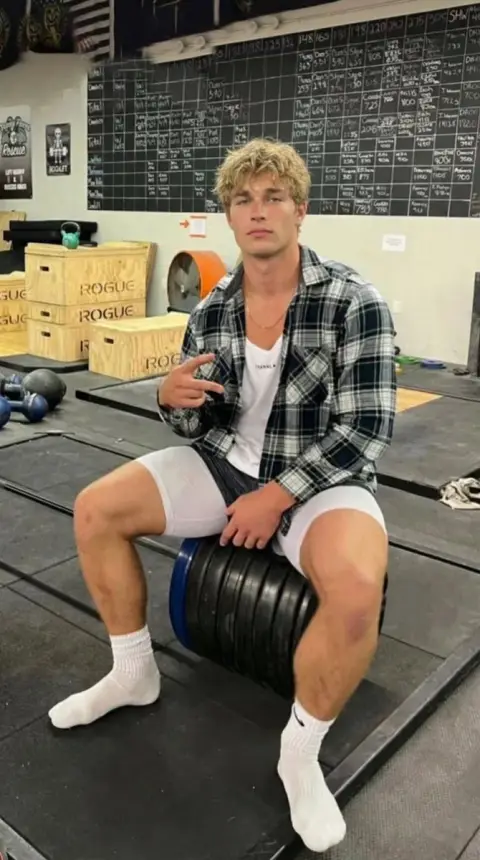 Handsome blond sportsman sitting on barbell plates