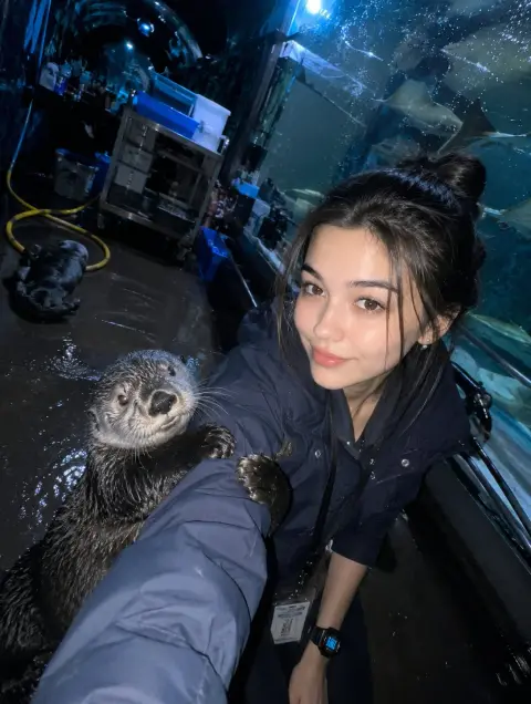 Keeper takes selfie with sea otter in dimmed aquarium tunnel