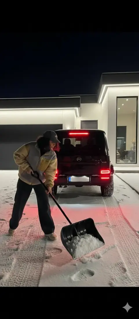 Mercedes Benz and snow plowing girl in front of a mansion on a snowy night