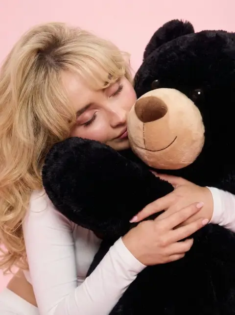 Millennial sweetheart sits astride giant black bear