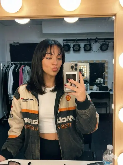 Playful mirror selfie of girl in retro racing jacket