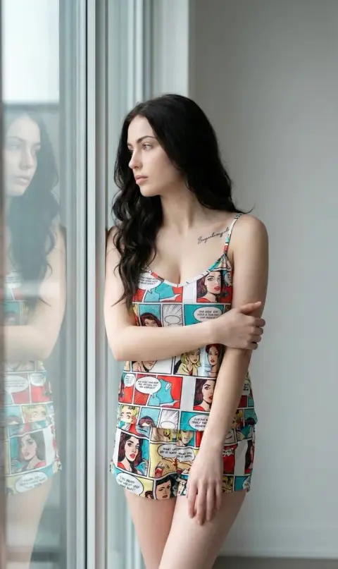 Pop-style black-haired girl in pajamas meditating by the window