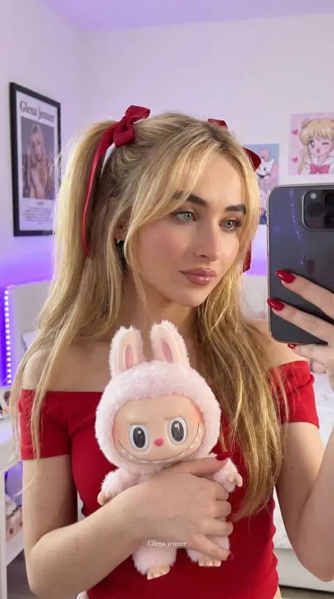 Realistic selfie of girl with red twintails holding doll in bedroom