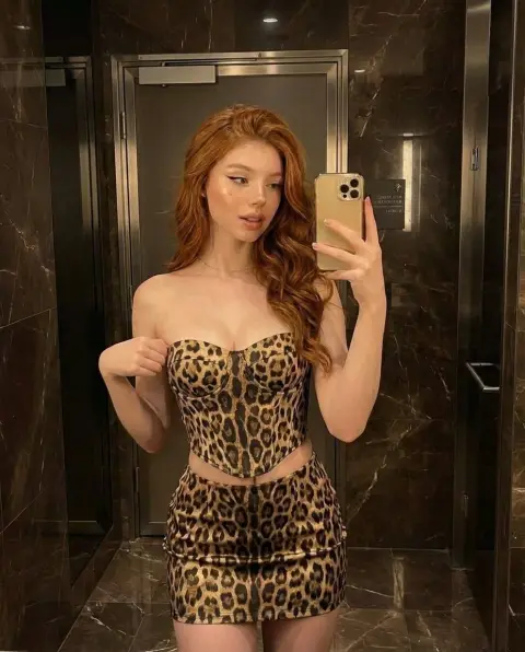 Redhead wearing leopard print selfie in warm light bathroom
