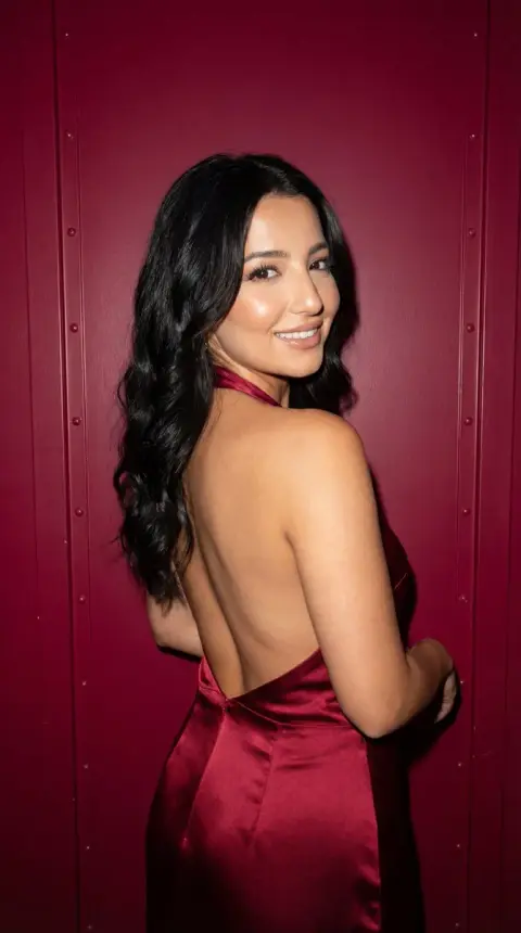 Review photo of the texture of the backless satin skirt in front of the crimson velvet wall