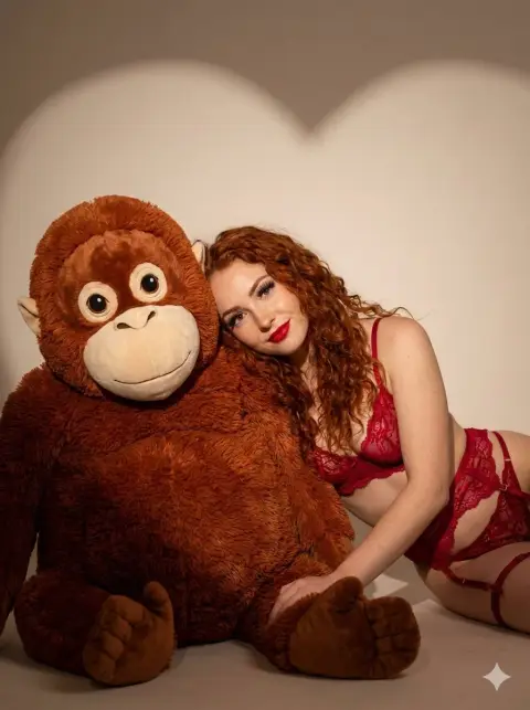 Romantic light and shadow of red-haired beauty cuddling to stuffed gorilla