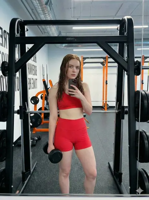 Rose pink sports girl takes a selfie in front of the mirror in a cool industrial style gym