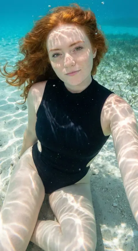 Sexy beauty in caramel-colored swimsuit overlooking the crystal clear sea