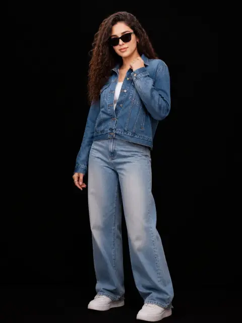 Street style portrait of fashionable curly woman in denim suit