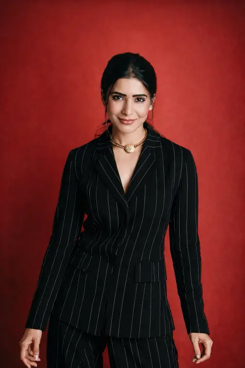 Studio portrait of woman in dark blue striped suit with red background