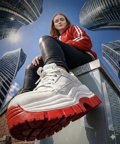 The girl in red clothes and trendy shoes on the rooftop under the fisheye lens