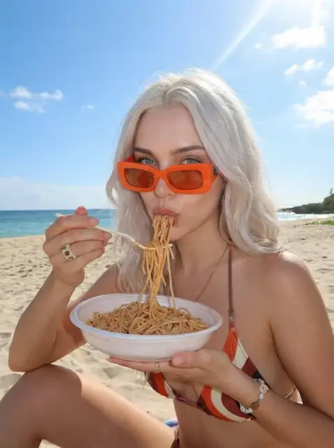 The pleasant moment of a blonde girl sucking pasta by the sunshine and blue sea